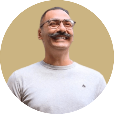 Photo of a man with glasses and moustache smiling wearing a grey sweater.